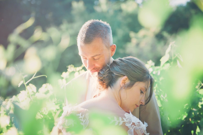 Moment de tendresse capturé par un photographe de mariage : un couple s'étreint doucement dans la lumière naturelle de Bordeaux.