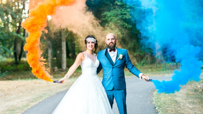 Couple de mariés célébrant avec des fumigènes colorés lors d'un mariage à Bordeaux, immortalisé par La Focale d'Olga.