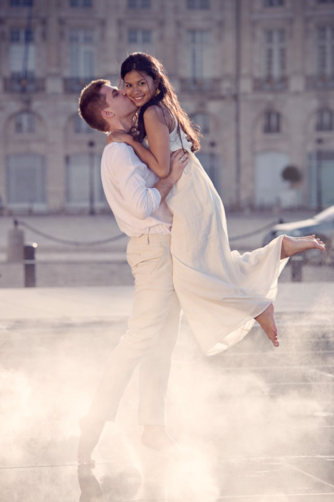 Couple heureux capturé par La Focale d'Olga, photographe de mariage à Bordeaux, dans une pose romantique sur le miroir d'eau.