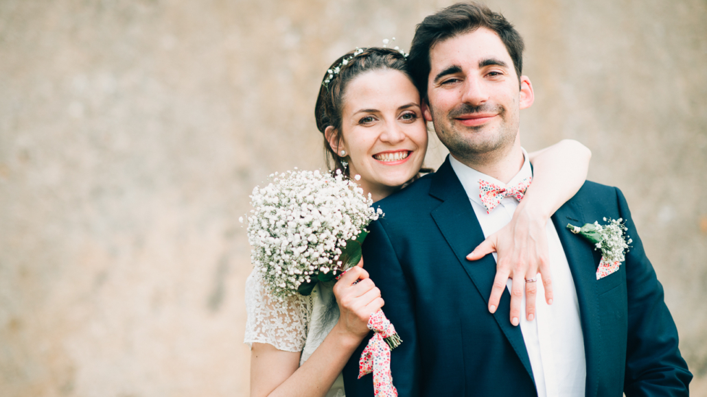 Couple radieux capturé par La Focale d'Olga, photographe spécialisée dans les mariages à Bordeaux, tenant un bouquet de gypsophile.